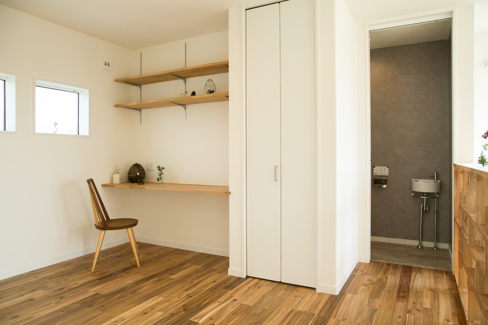 Idée de décoration pour une salle de séjour minimaliste avec une bibliothèque ou un coin lecture, un sol en bois brun et un sol marron.