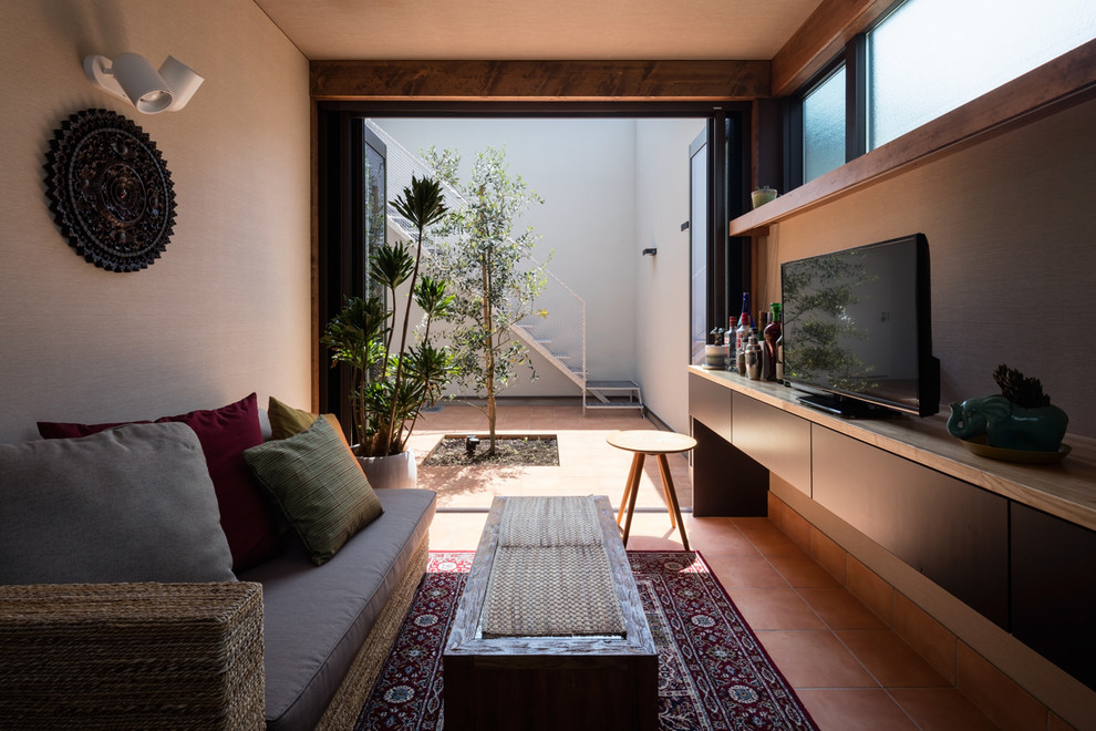 Idee per un soggiorno etnico chiuso con pareti bianche, pavimento in terracotta, TV autoportante, pavimento arancione e angolo bar