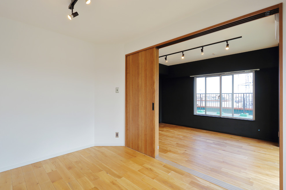 Immagine di un soggiorno minimalista di medie dimensioni e aperto con pareti nere, pavimento in legno massello medio, nessun camino e pavimento marrone