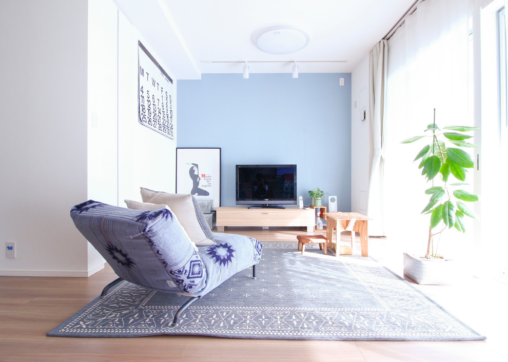 東京23区にあるビーチスタイルのおしゃれなファミリールーム (青い壁、淡色無垢フローリング、据え置き型テレビ、茶色い床) の写真