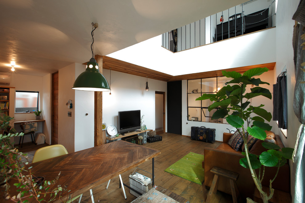 Foto di un soggiorno industriale aperto con pareti bianche, pavimento in legno massello medio e TV autoportante
