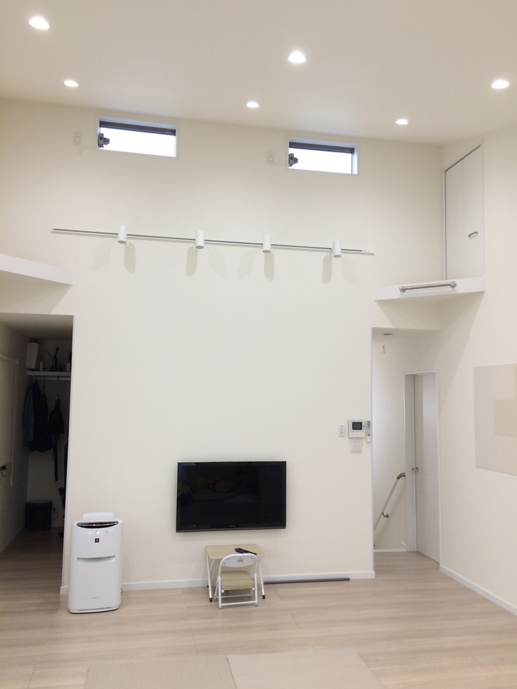 Foto di un soggiorno minimalista con pareti bianche, pavimento in compensato, TV a parete e pavimento marrone