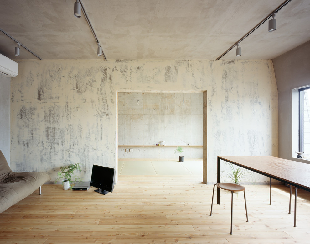 Inredning av ett industriellt allrum, med grå väggar, ljust trägolv, en fristående TV och brunt golv