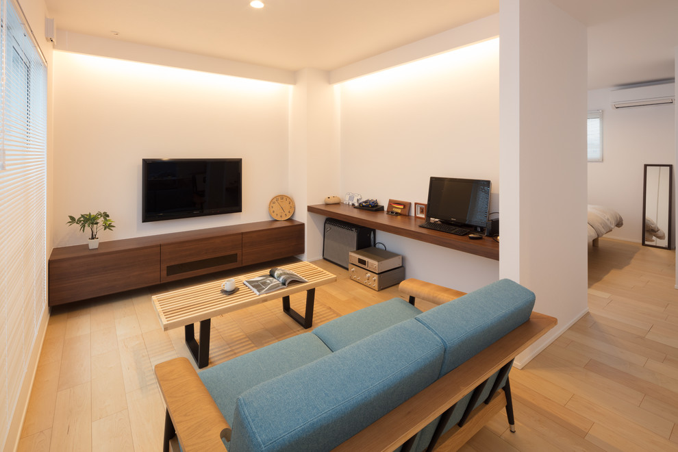 Cette image montre une salle de séjour minimaliste avec un mur blanc, parquet clair, un téléviseur fixé au mur et un sol beige.