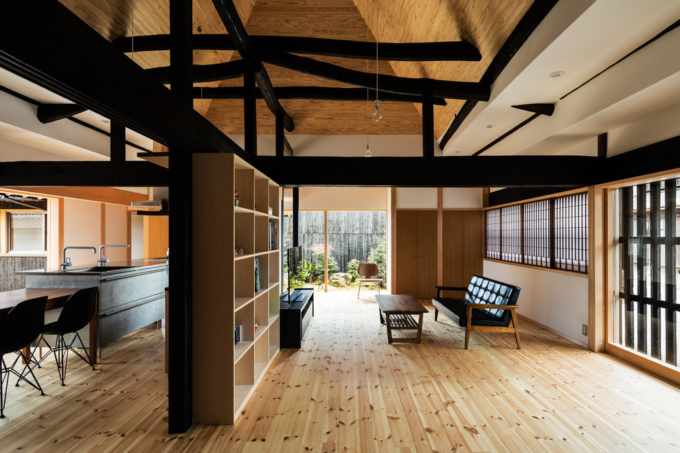 Imagen de sala de estar abierta de estilo zen con paredes blancas, suelo de madera clara, televisor independiente y suelo marrón