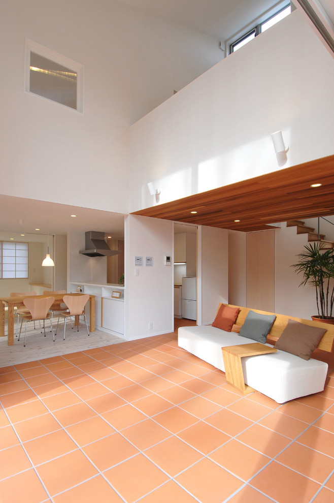 Пример оригинального дизайна: открытая гостиная комната среднего размера в скандинавском стиле с белыми стенами, полом из терракотовой плитки и отдельно стоящим телевизором без камина