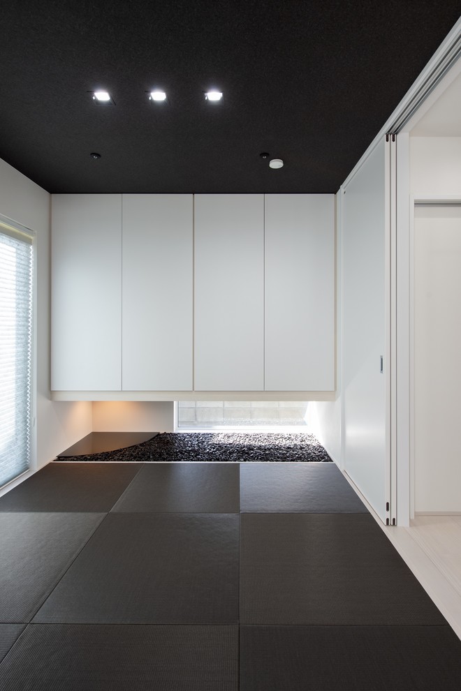 Cette image montre une salle de séjour asiatique fermée avec un mur blanc, un sol de tatami et un sol noir.