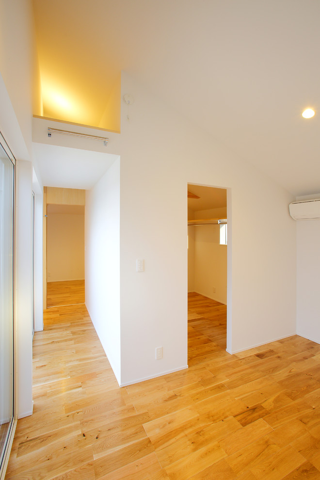 Imagen de sala de estar contemporánea con paredes blancas, suelo de madera clara y suelo marrón