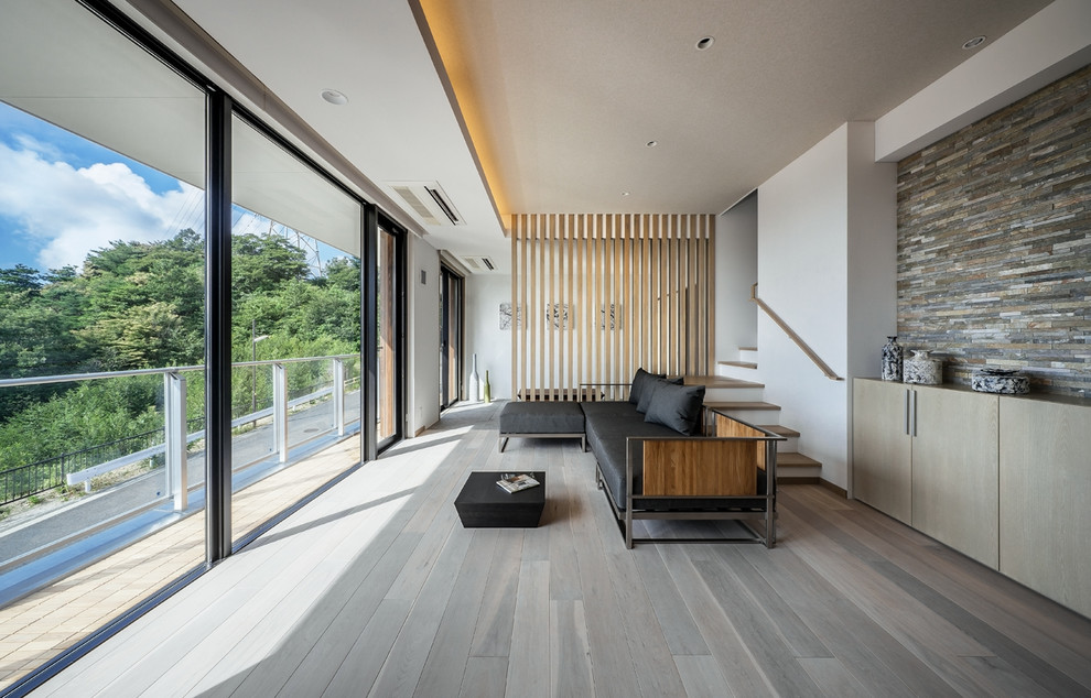 Offenes Modernes Wohnzimmer ohne Kamin mit weißer Wandfarbe, Sperrholzboden und freistehendem TV in Osaka