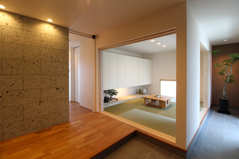 Immagine di una sala da pranzo etnica con pareti bianche, pavimento in tatami e pavimento verde