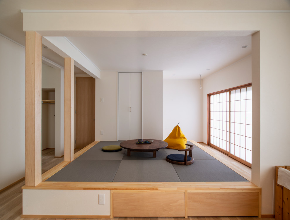 Exemple d'une petite salle de séjour asiatique ouverte avec un mur blanc, un sol de tatami et un sol gris.