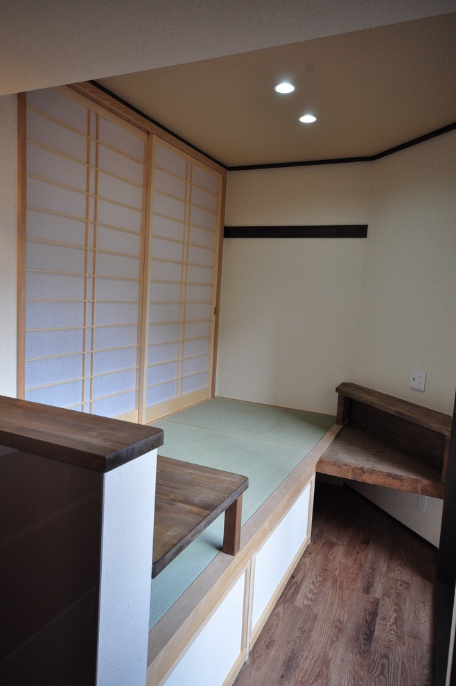 Réalisation d'une salle de séjour asiatique avec un mur beige, un téléviseur d'angle et un sol marron.