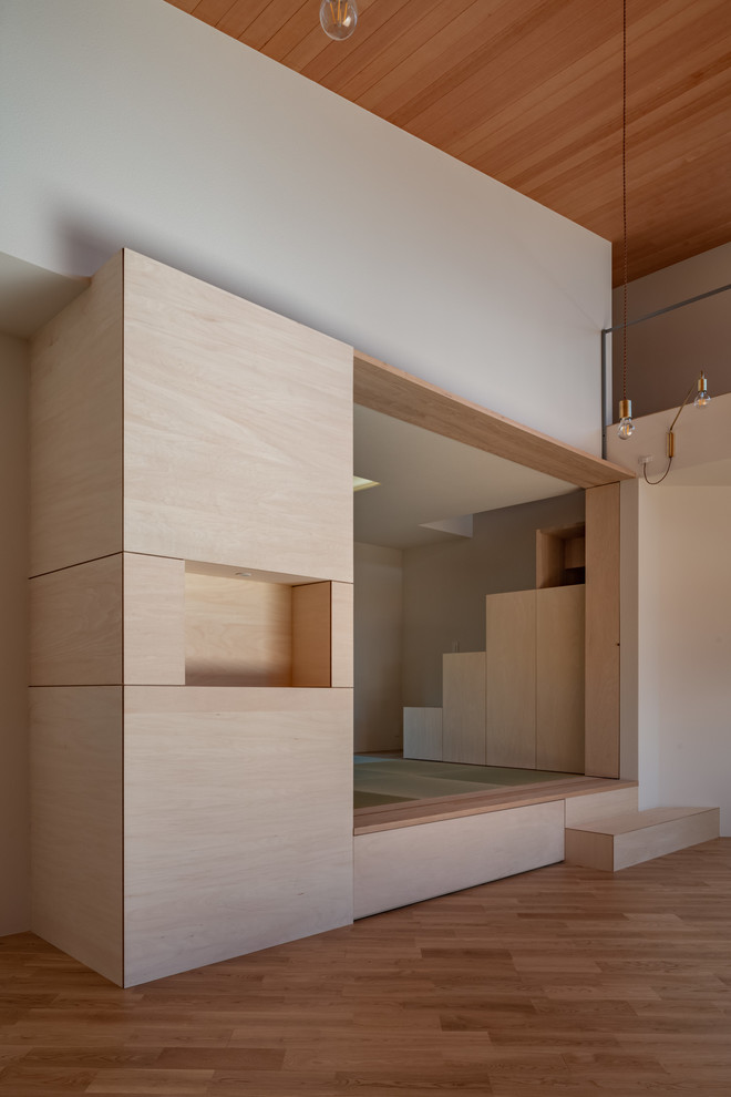 Ejemplo de sala de estar abierta de estilo zen de tamaño medio con paredes blancas, suelo de madera en tonos medios, pared multimedia y suelo marrón