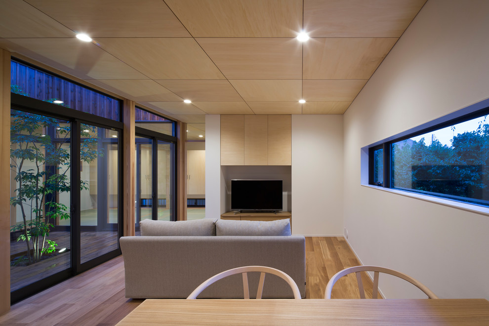 Ejemplo de sala de estar abierta asiática con paredes blancas, suelo de madera en tonos medios, televisor independiente y suelo marrón