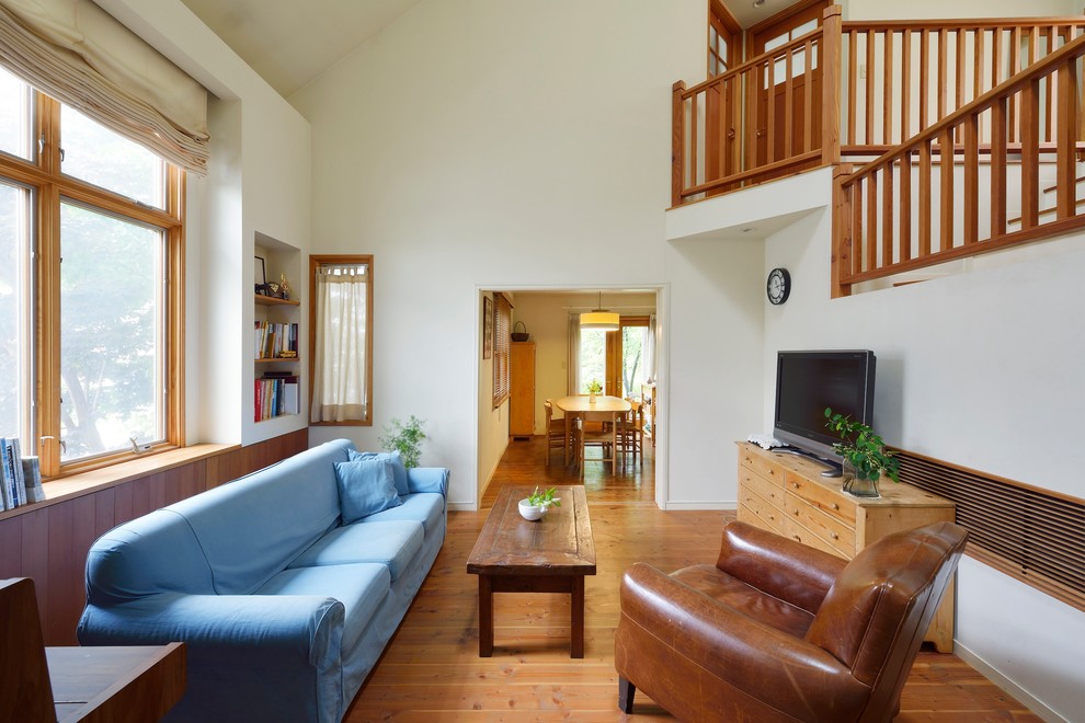 Esempio di un grande soggiorno country con pareti bianche, pavimento in legno massello medio, nessun camino, TV autoportante e pavimento marrone