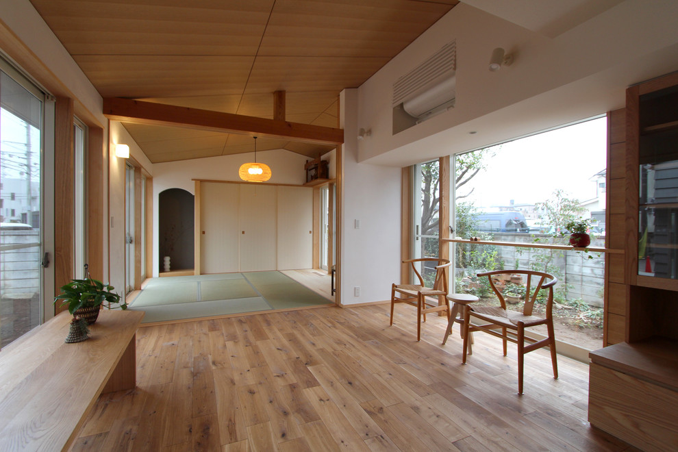 На фото: открытая гостиная комната в восточном стиле с белыми стенами, паркетным полом среднего тона и коричневым полом