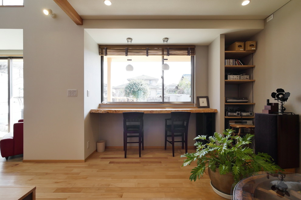Modelo de despacho asiático con paredes blancas, suelo de madera en tonos medios y suelo marrón