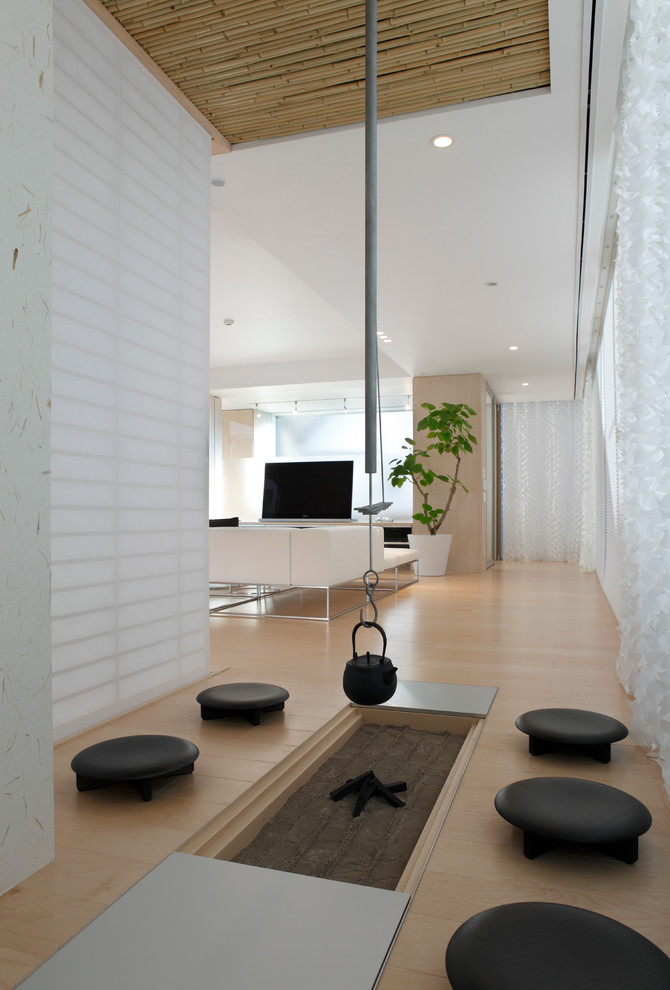 Diseño de sala de estar abierta de estilo zen con paredes blancas, suelo de madera clara y televisor independiente
