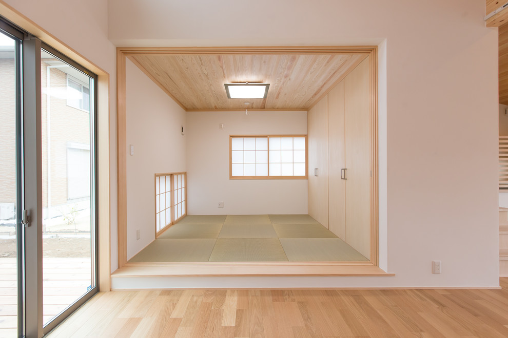 Diseño de sala de estar con biblioteca cerrada asiática pequeña sin televisor con paredes blancas, tatami y suelo verde