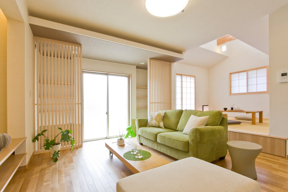 Modelo de sala de estar abierta de estilo zen con paredes blancas, suelo de madera clara y suelo beige