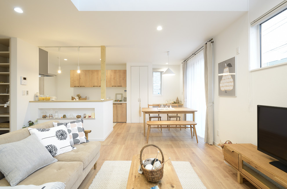 Источник вдохновения для домашнего уюта: открытая гостиная комната в скандинавском стиле с белыми стенами, деревянным полом, отдельно стоящим телевизором и бежевым полом