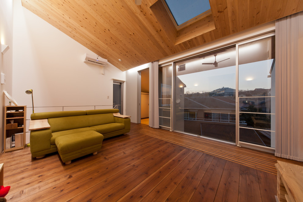 Exemple d'une salle de séjour tendance fermée avec un mur blanc, un sol en bois brun et un sol marron.