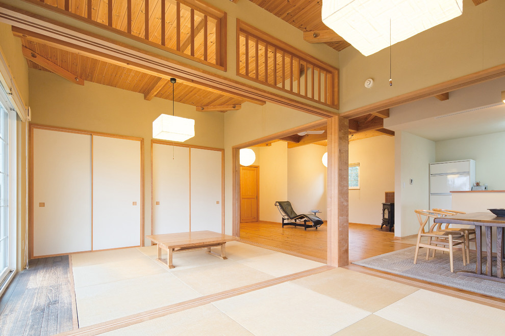 Esempio di un soggiorno etnico aperto con pareti bianche, pavimento in legno massello medio, stufa a legna, cornice del camino in mattoni e pavimento marrone