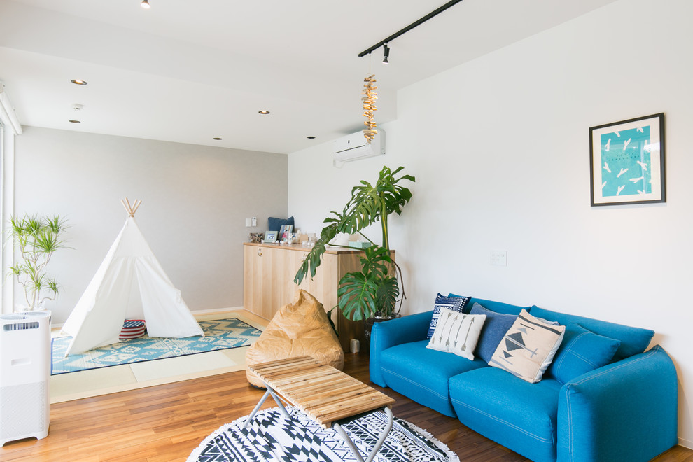 Diseño de sala de estar costera con paredes blancas, suelo de madera en tonos medios, televisor colgado en la pared y suelo marrón