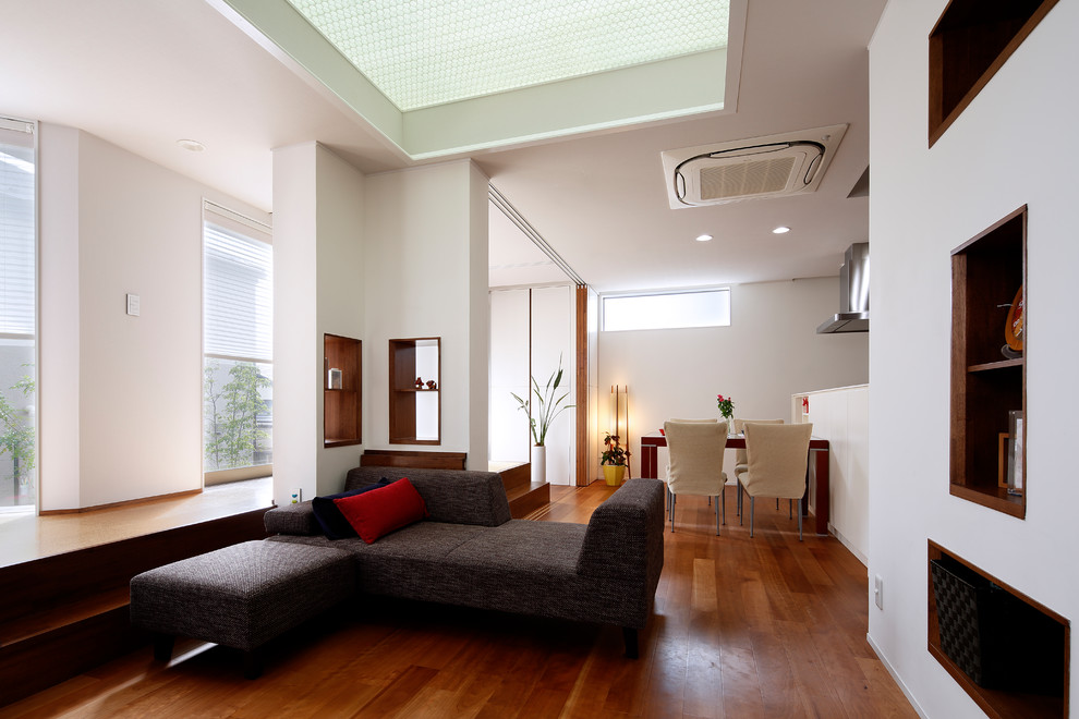 Foto de sala de estar abierta contemporánea sin chimenea con paredes blancas, suelo de madera en tonos medios y suelo marrón