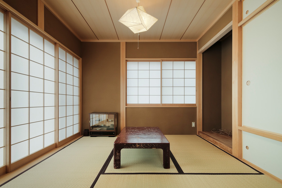 Cette image montre une salle de séjour asiatique avec un mur marron, un sol de tatami et un sol marron.