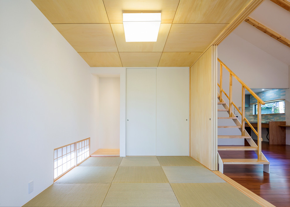 Cette image montre une salle de séjour asiatique avec un mur blanc, un sol de tatami et un sol vert.
