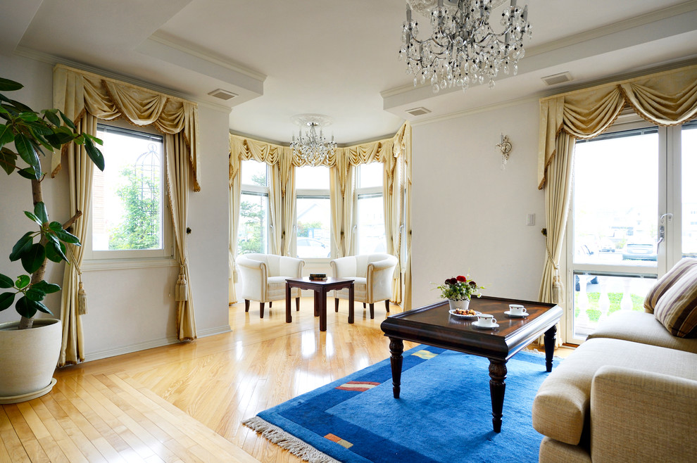 Modelo de sala de estar abierta clásica grande con paredes blancas, suelo de madera clara, estufa de leña y marco de chimenea de baldosas y/o azulejos
