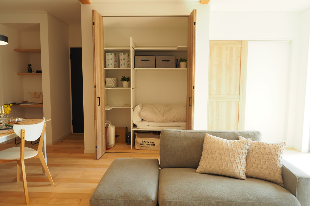 Exempel på ett mellanstort allrum, med vita väggar, ljust trägolv, en fristående TV och beiget golv