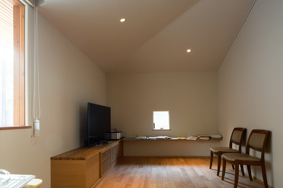 Стильный дизайн: изолированная гостиная комната среднего размера в восточном стиле с с книжными шкафами и полками, бежевыми стенами, паркетным полом среднего тона, отдельно стоящим телевизором и коричневым полом без камина - последний тренд