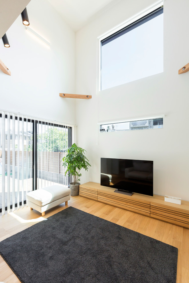 Modernes Wohnzimmer ohne Kamin mit weißer Wandfarbe, freistehendem TV und hellem Holzboden in Sonstige