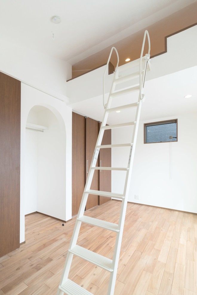 Aménagement d'une salle de séjour mansardée ou avec mezzanine éclectique avec un mur blanc, un sol en bois brun et un sol marron.