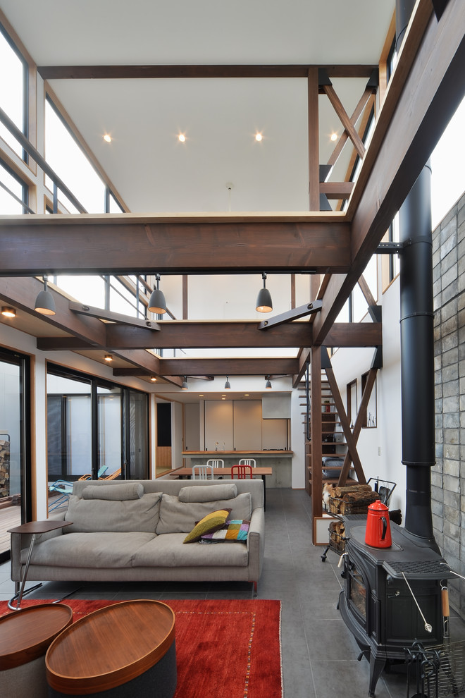 Idee per un soggiorno industriale aperto con pareti bianche, stufa a legna e cornice del camino piastrellata