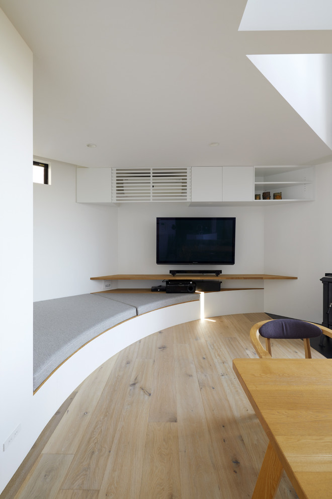 Esempio di un soggiorno minimalista con pareti bianche, parquet chiaro, TV a parete e pavimento beige