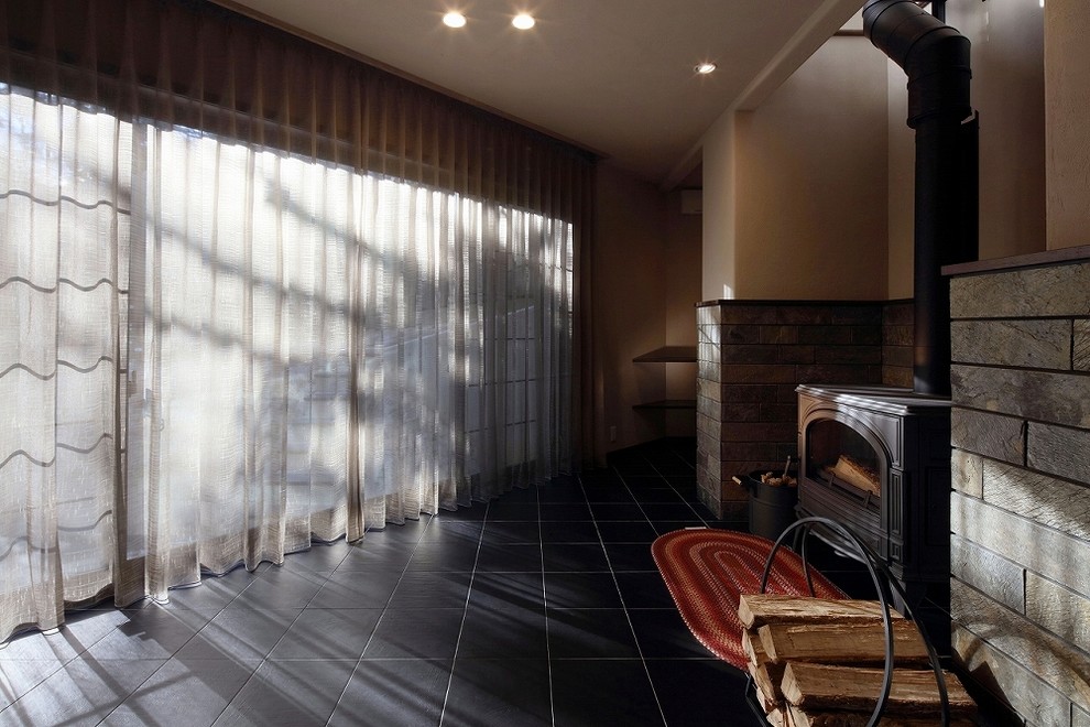 名古屋にある広いミッドセンチュリースタイルのおしゃれなファミリールーム (磁器タイルの床、薪ストーブ、レンガの暖炉まわり、グレーの床) の写真
