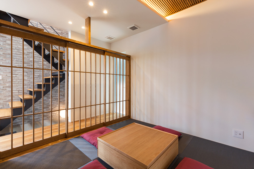 Réalisation d'une salle de séjour asiatique fermée avec un mur blanc, un sol de tatami et un sol gris.