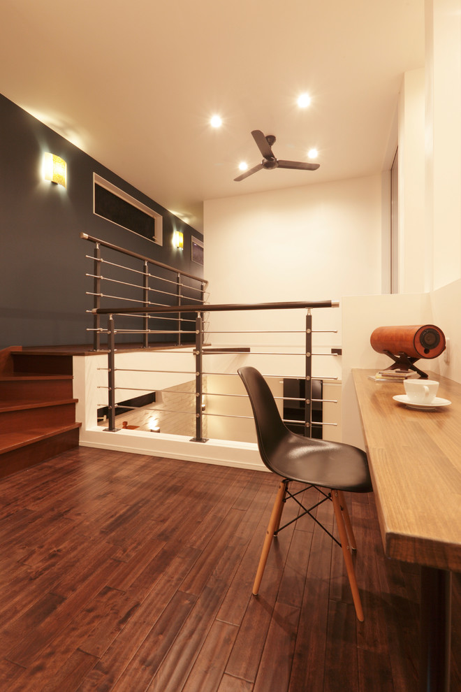 Cette image montre une salle de séjour minimaliste avec un mur gris, parquet foncé et un sol marron.