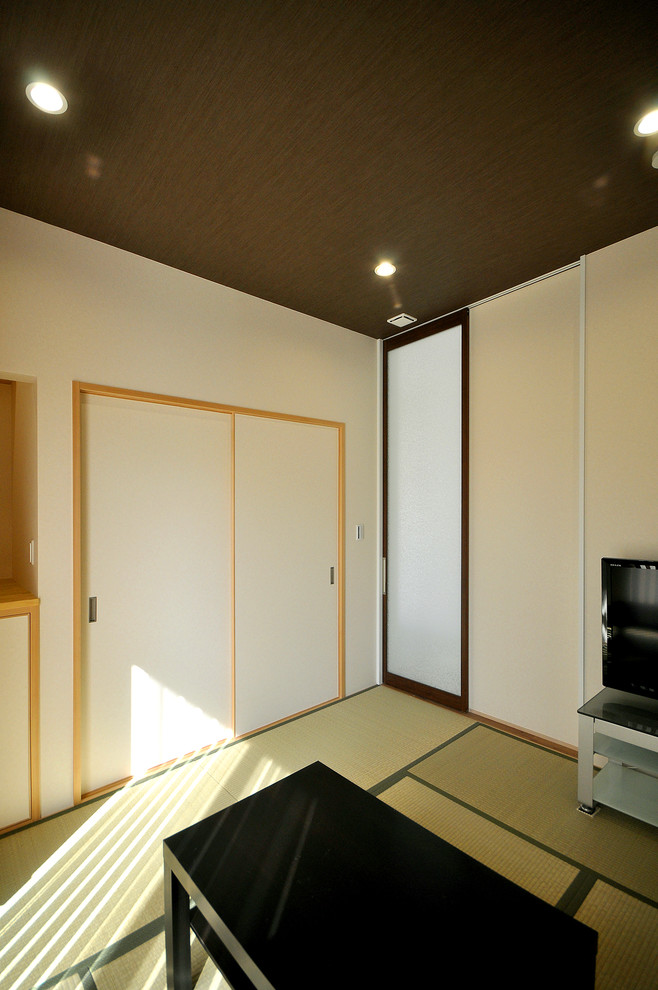 Abgetrenntes Modernes Wohnzimmer ohne Kamin mit weißer Wandfarbe, Tatami-Boden, freistehendem TV und grünem Boden in Sonstige