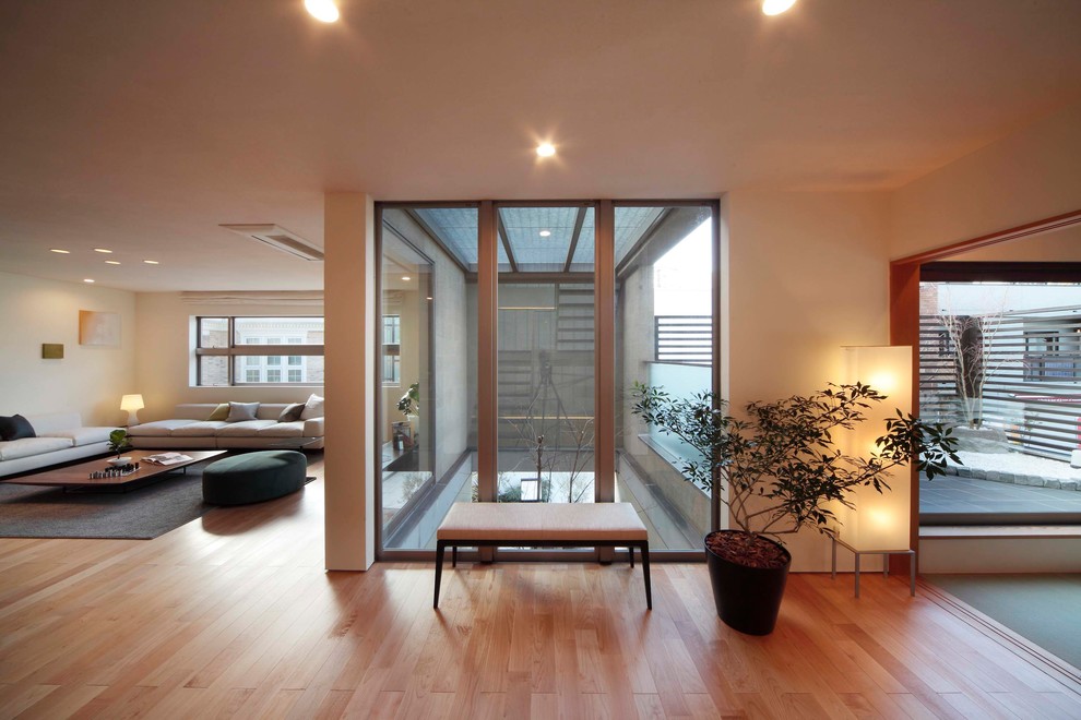 Asiatisches Wohnzimmer mit weißer Wandfarbe, hellem Holzboden und braunem Boden in Tokio