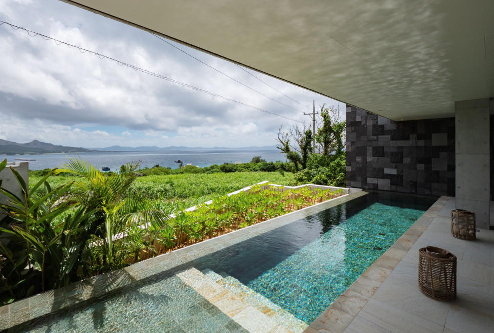 Imagen de casa de la piscina y piscina infinita de estilo zen grande a medida en patio delantero con adoquines de hormigón