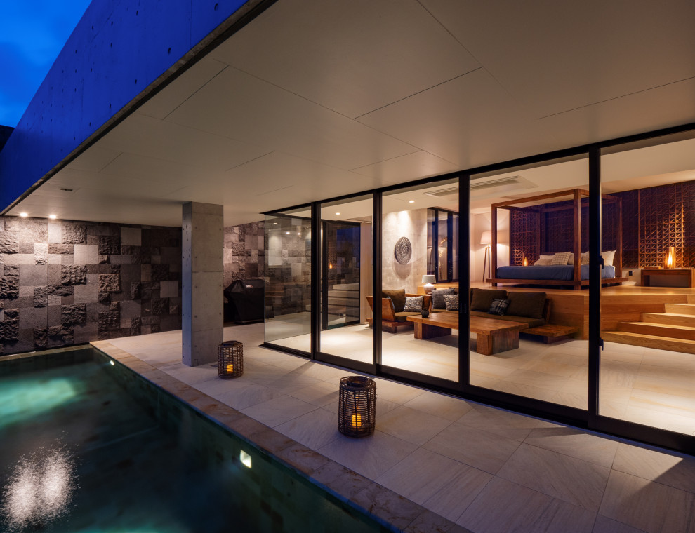 Imagen de casa de la piscina y piscina infinita asiática grande a medida en patio delantero con adoquines de hormigón