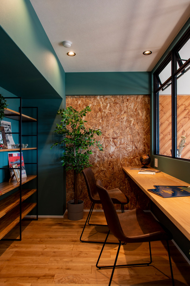 Foto de despacho industrial sin chimenea con paredes verdes, suelo de madera en tonos medios y escritorio empotrado