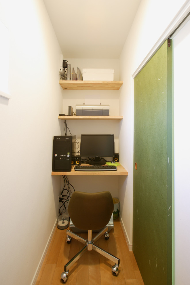 他の地域にある小さなモダンスタイルのおしゃれなホームオフィス・書斎 (白い壁、無垢フローリング、造り付け机、茶色い床) の写真