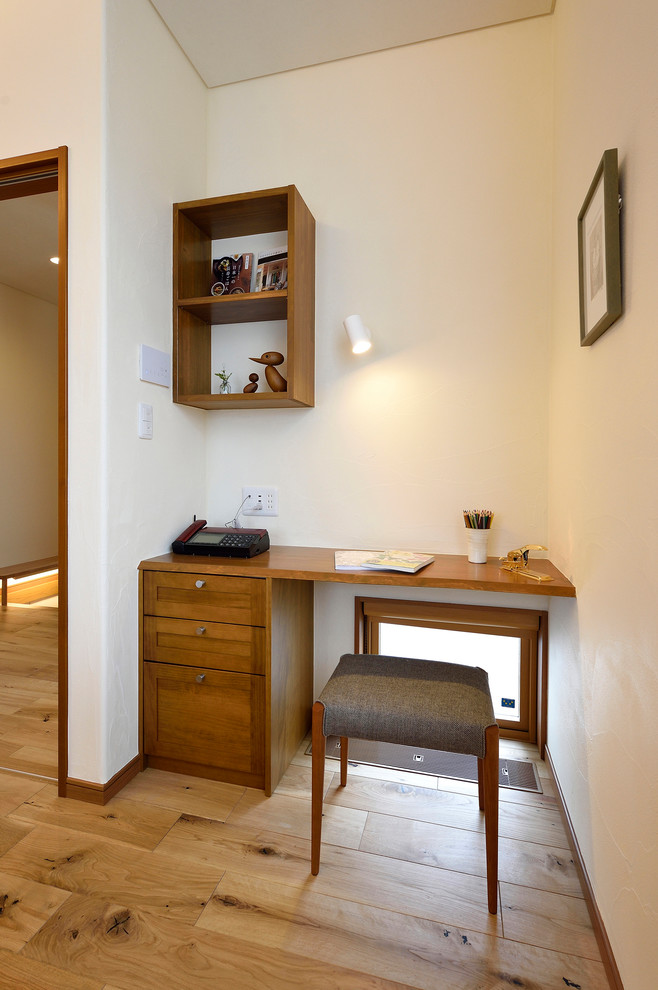 Immagine di un piccolo ufficio etnico con pareti bianche, pavimento in legno massello medio, nessun camino, scrivania incassata e pavimento marrone