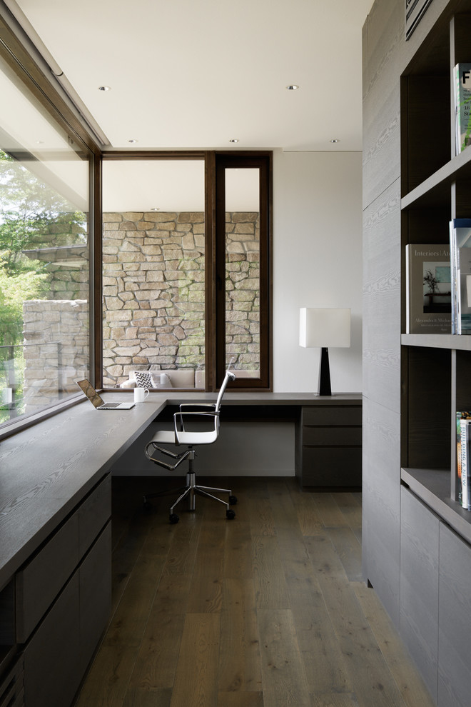 Exempel på ett modernt arbetsrum, med vita väggar, målat trägolv, ett inbyggt skrivbord och grått golv