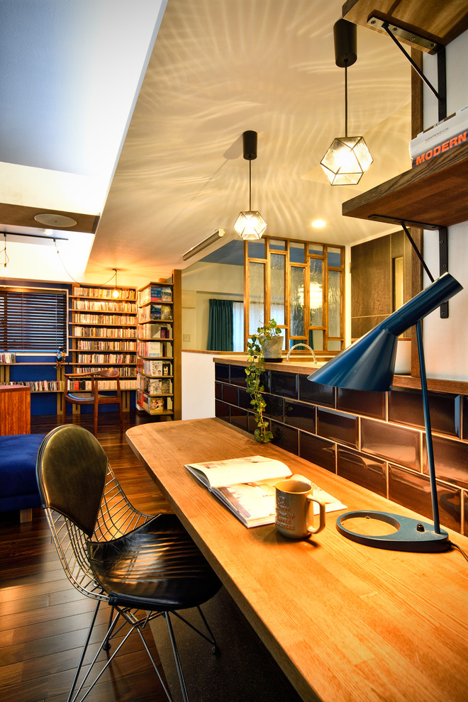 他の地域にあるインダストリアルスタイルのおしゃれなホームオフィス・書斎 (白い壁、濃色無垢フローリング、造り付け机、茶色い床) の写真
